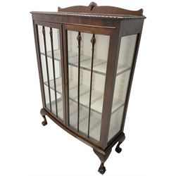 Early 20th century figured walnut bow-front display cabinet, enclosed by two glazed doors, on ball and claw cabriole feet