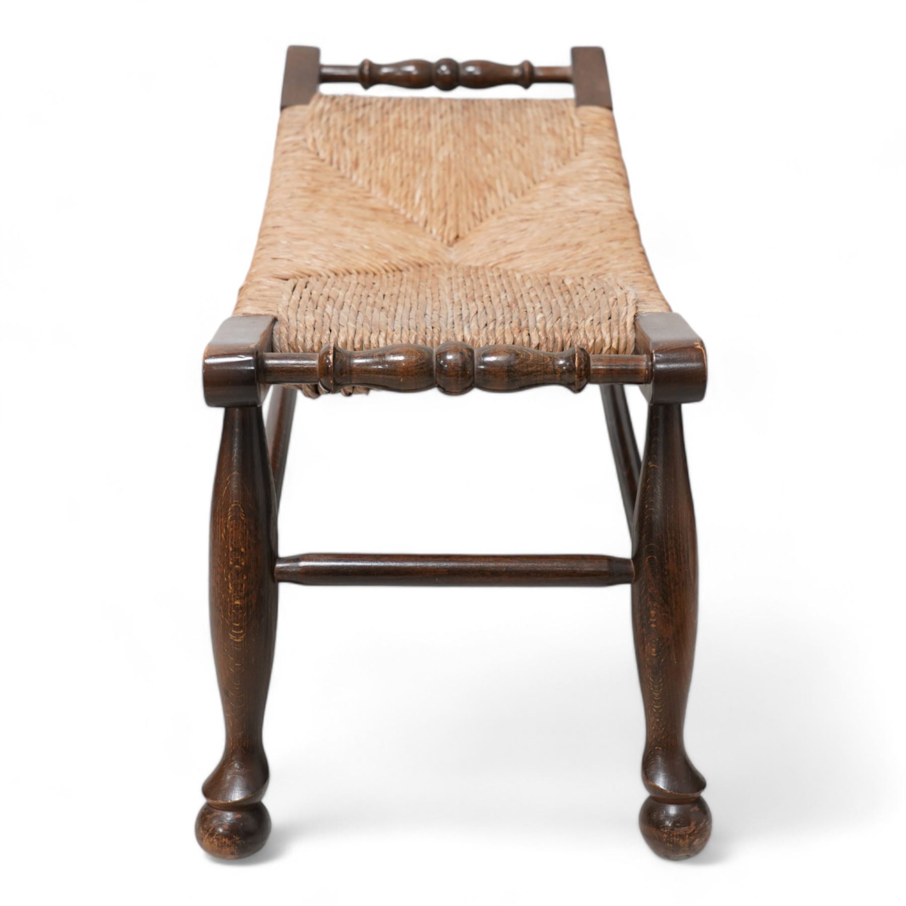 Arts & Crafts design stained beech framed stool, dished top with rush seat, on turned supports united by stretchers 