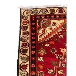 Persian crimson ground rug, the field decorated with three medallions within stepped borders, decorated all over with small stylised plant motifs, trailing flower head outer band and floral pattern border 