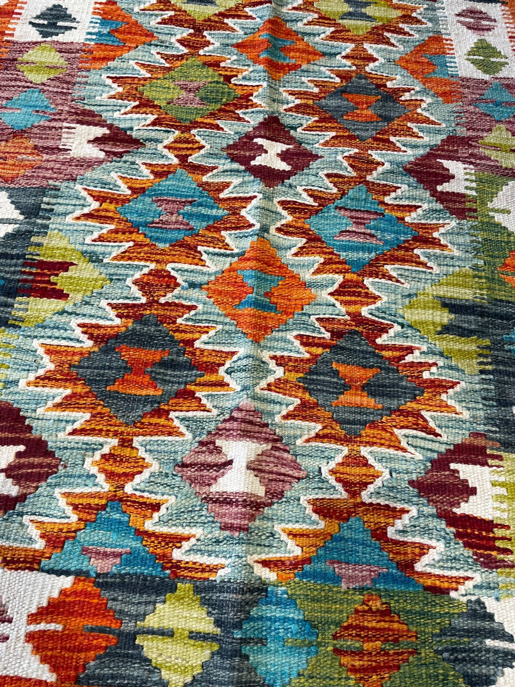 Chobi Kilim ivory ground rug, the busy multi-coloured field decorated with two concentric lozenges, the guard lines decorated with broken-lozenge motifs and geometric designs