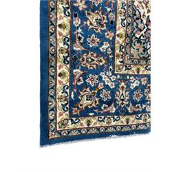 Persian Nain blue ground carpet, overall arabesque design, centre rosette medallion with eight projecting palmettes, the surrounding field decorated with interlacing branches and stylised plant motifs, within floral pale ground spandrels, the guarded border decorated with repeating stylised floral pattern 