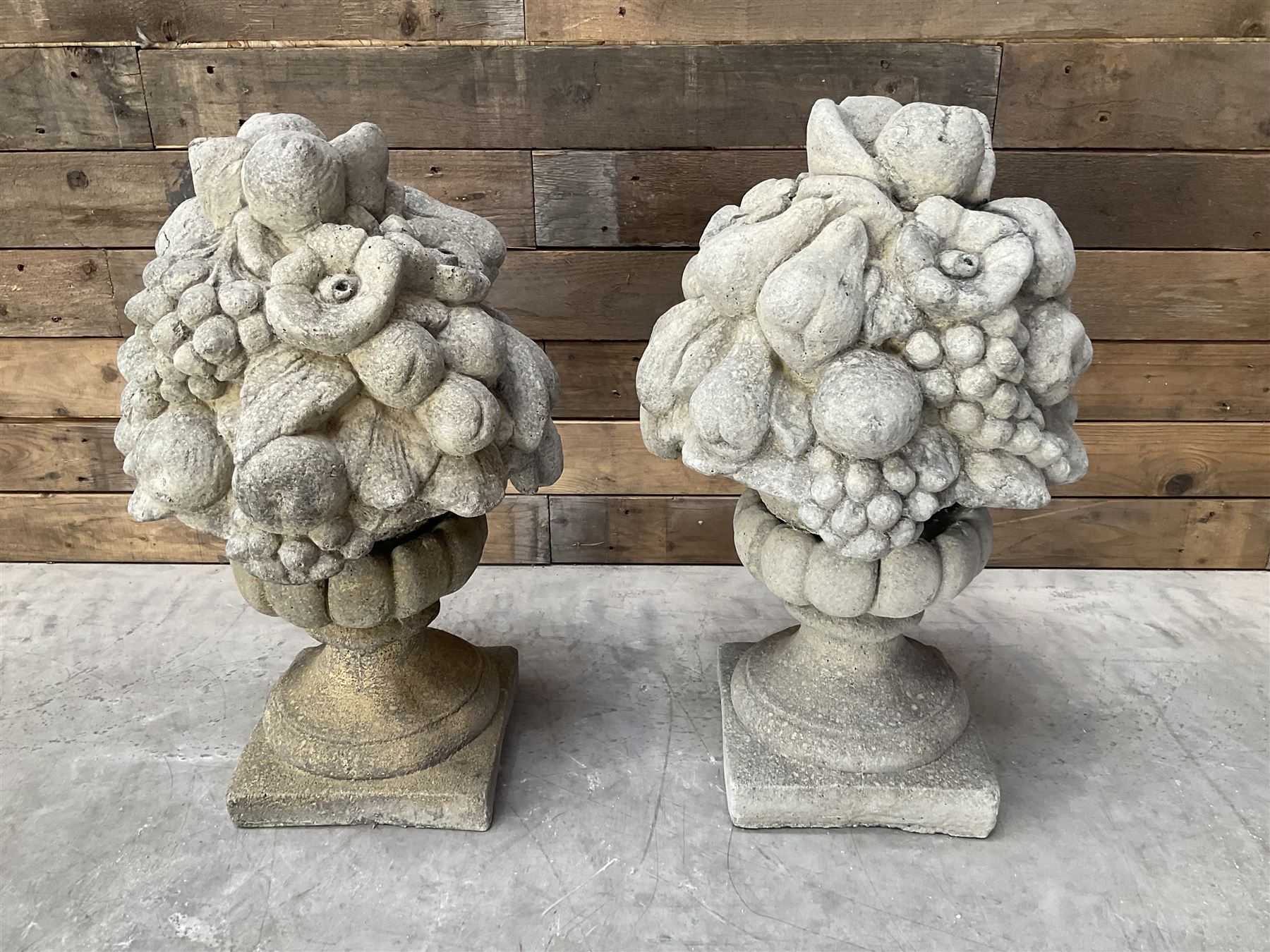 Pair of cast stone garden wall or gate finials depicting Fruit Piers, raised on separate circular squat column with plinth base