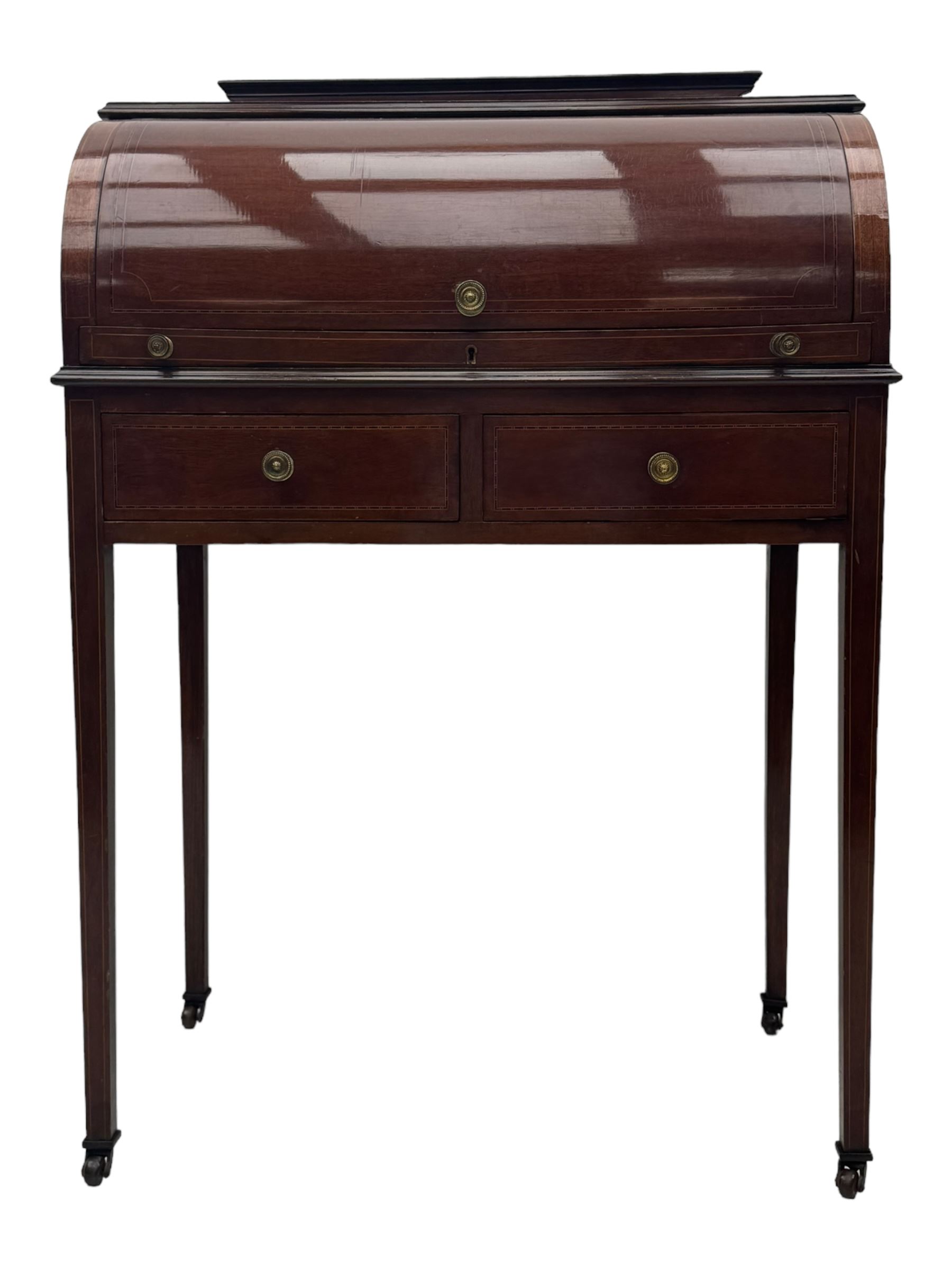 Edwardian inlaid mahogany roll-top desk, cylindrical lid enclosing fitted interior with pigeonholes, drawers and retractable writing surface, over two drawers with brass pull handles, on tapered supports with brass and ceramic castors