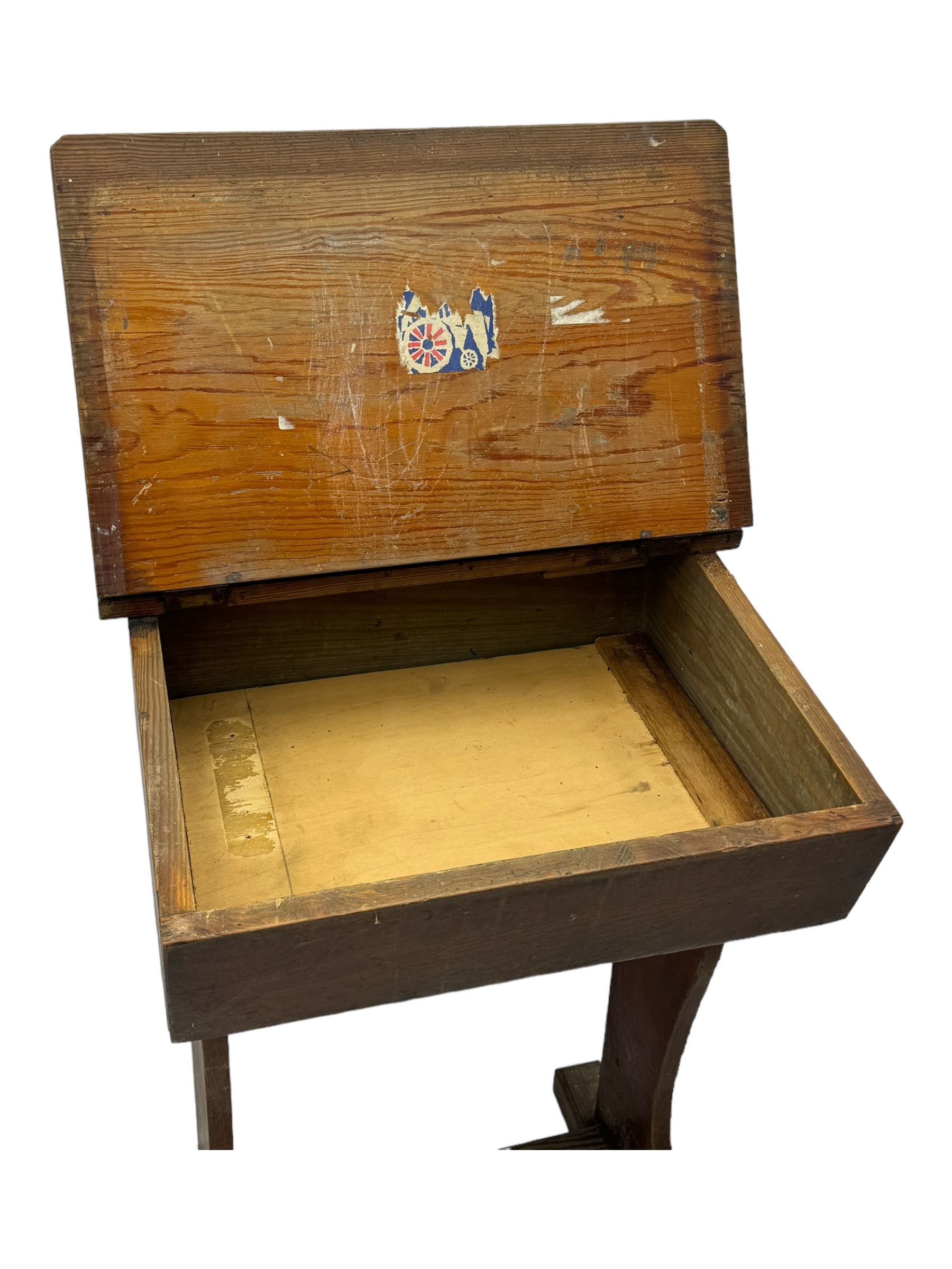 Three pitch pine school desks, each with rectangular lift-top with recessed ink well enclosing storage compartment, on trestle supports joined by stretcher