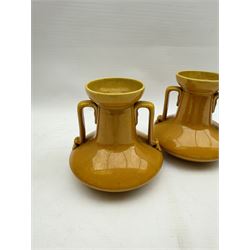 Christopher Dresser for Linthorpe Pottery, pair of twin handled vases, ochre glaze, H14cm