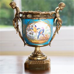 19th century French Sevres style porcelain and gilt brass urn, the body painted with panels of exotic birds and floral sprays within gilt borders on a bleu celeste ground, the handles formed as two cherubs seated upon grasses, upon a laurel leaf cast pedestal base, H20.5cm 