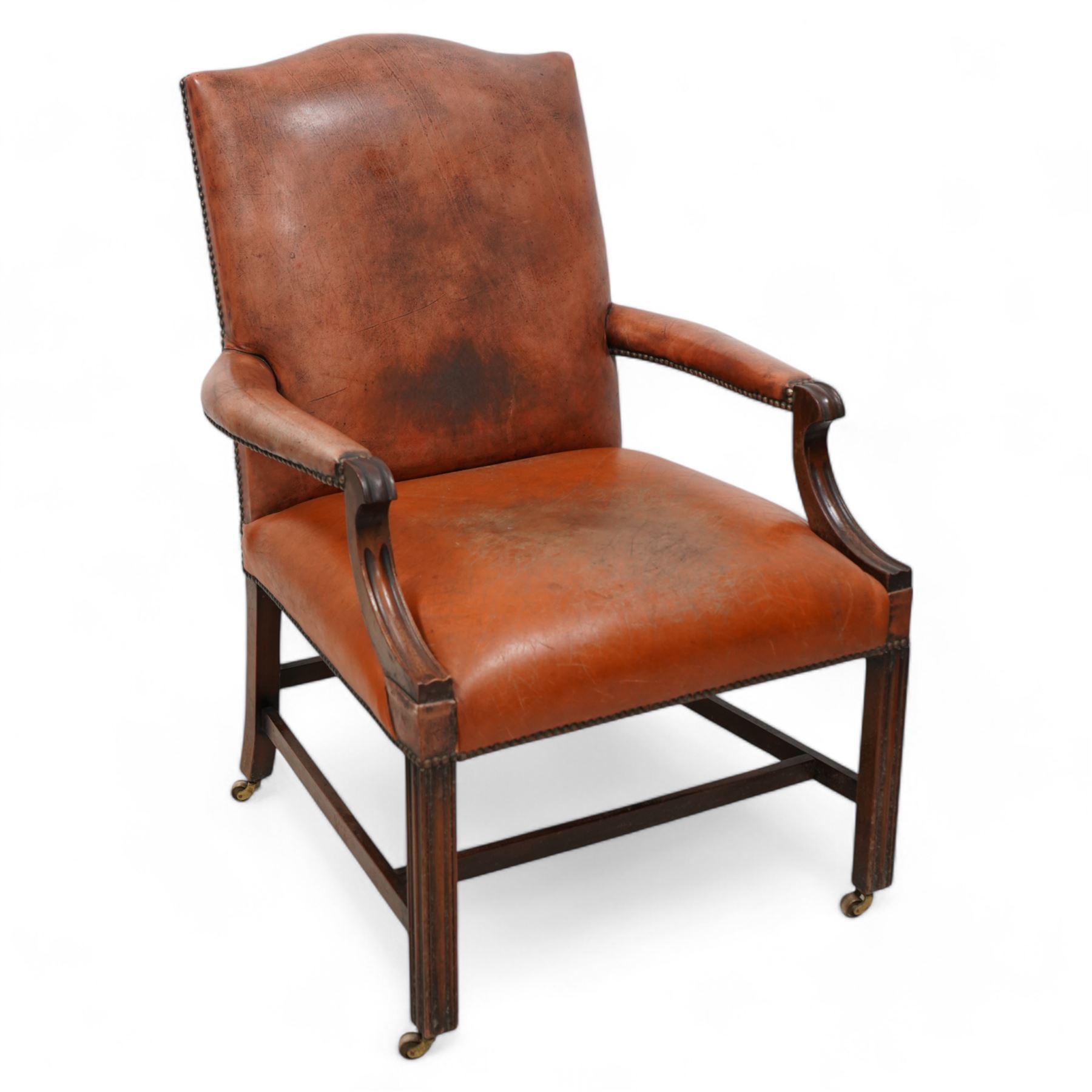 Georgian design Gainsborough elbow chair, upholstered in leather with studwork bands, moulded square supports united by H-stretcher, on brass castors 