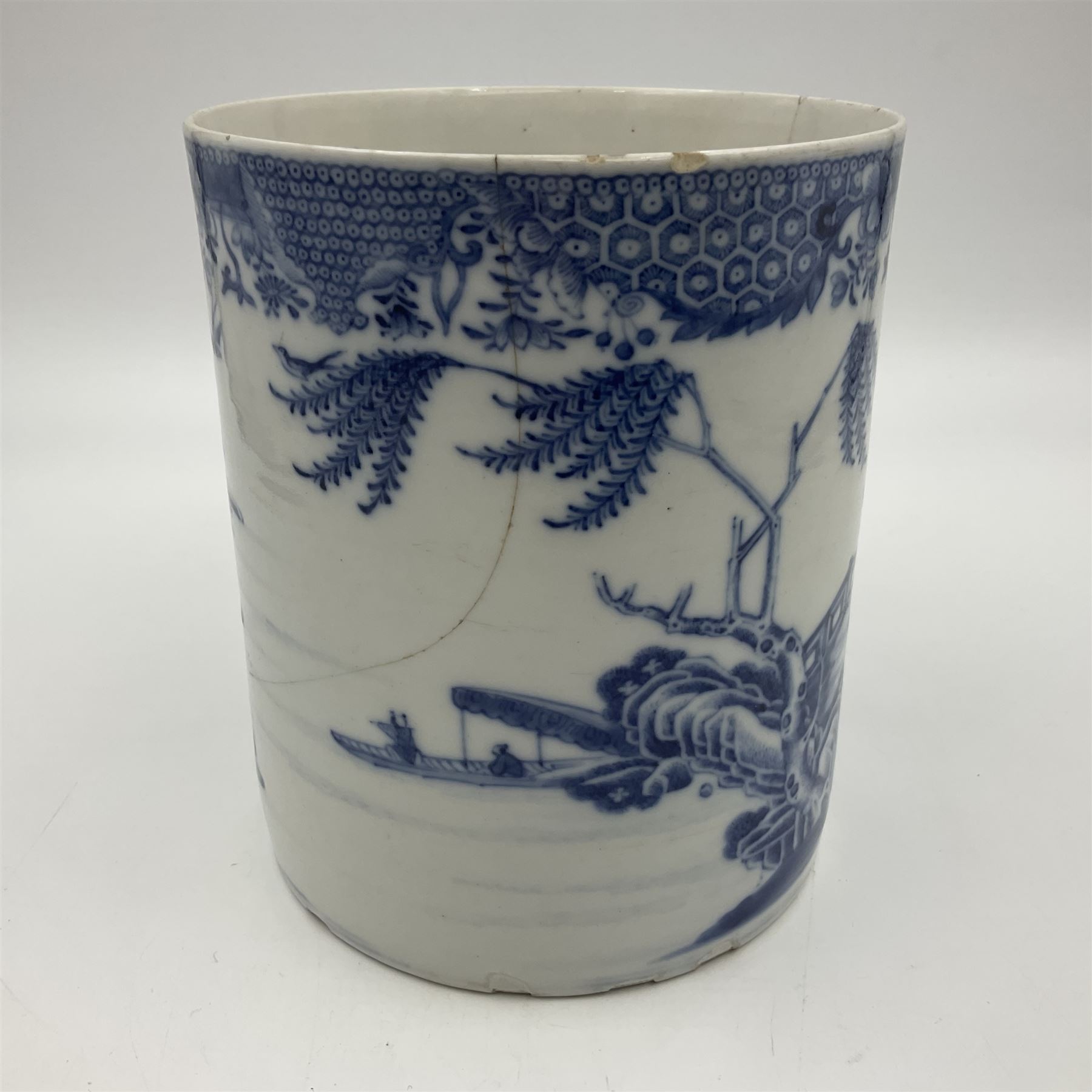 Two large 18th century Chinese blue and white tankards, each of cylindrical form, the first example with foliate mounted strap handle, the body painted with a shaped panel depicting a riverside landscape with pagodas and pine trees, against a textured ground decorated with floral sprays, H15cm D12cm, the second with serpent handle, the body painted with a similar riverside landscape, H14cm D12cm