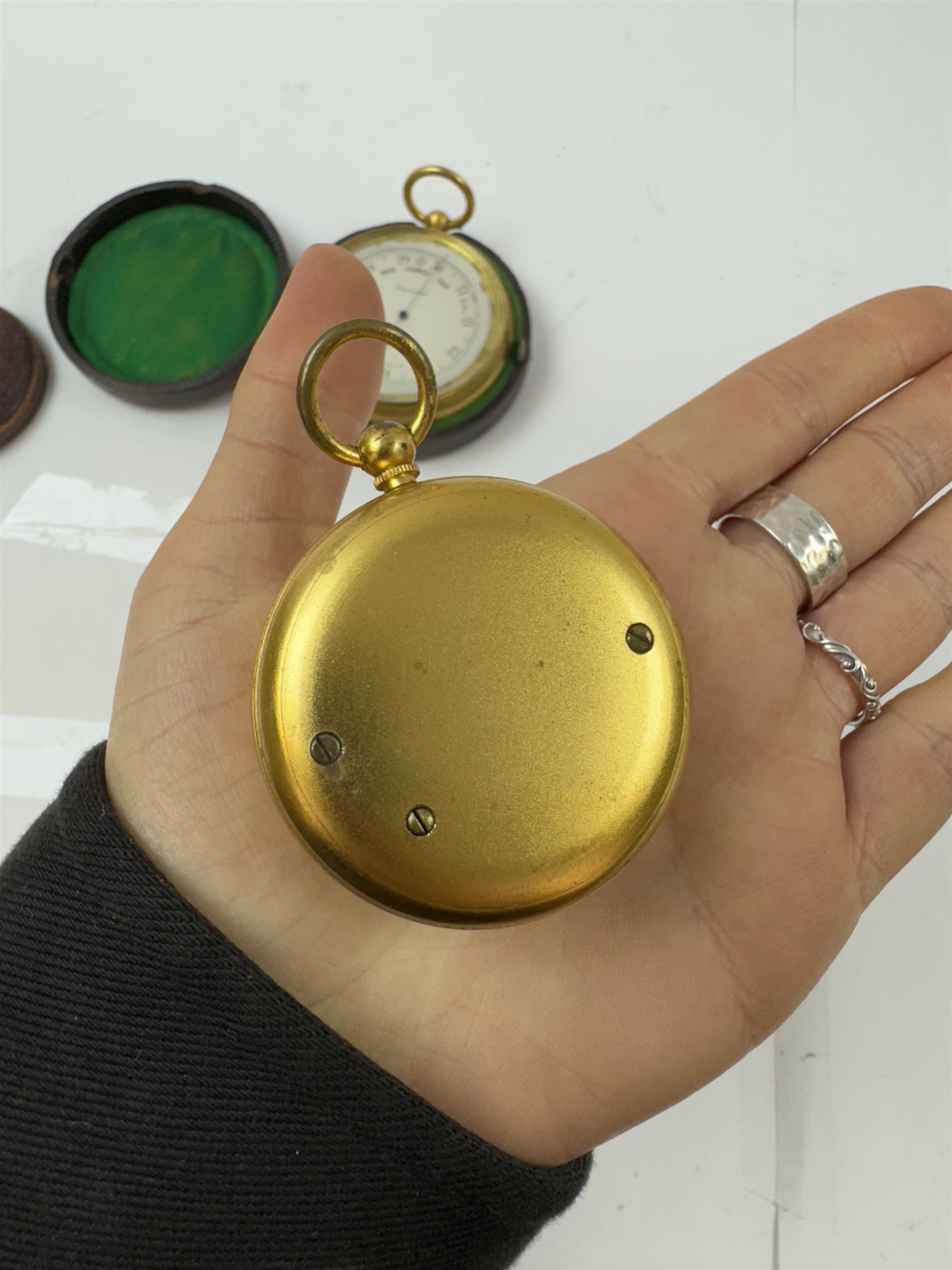 Lowdon Dundee, an early 20th century leather cased pocket barometer with silver dial, D4cm, together with another larger and later example, both cased