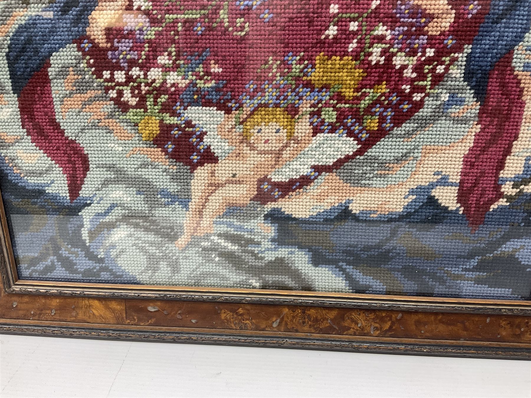 Two framed needlework samplers, the first example depicting a house and garden scene, the second cherubs