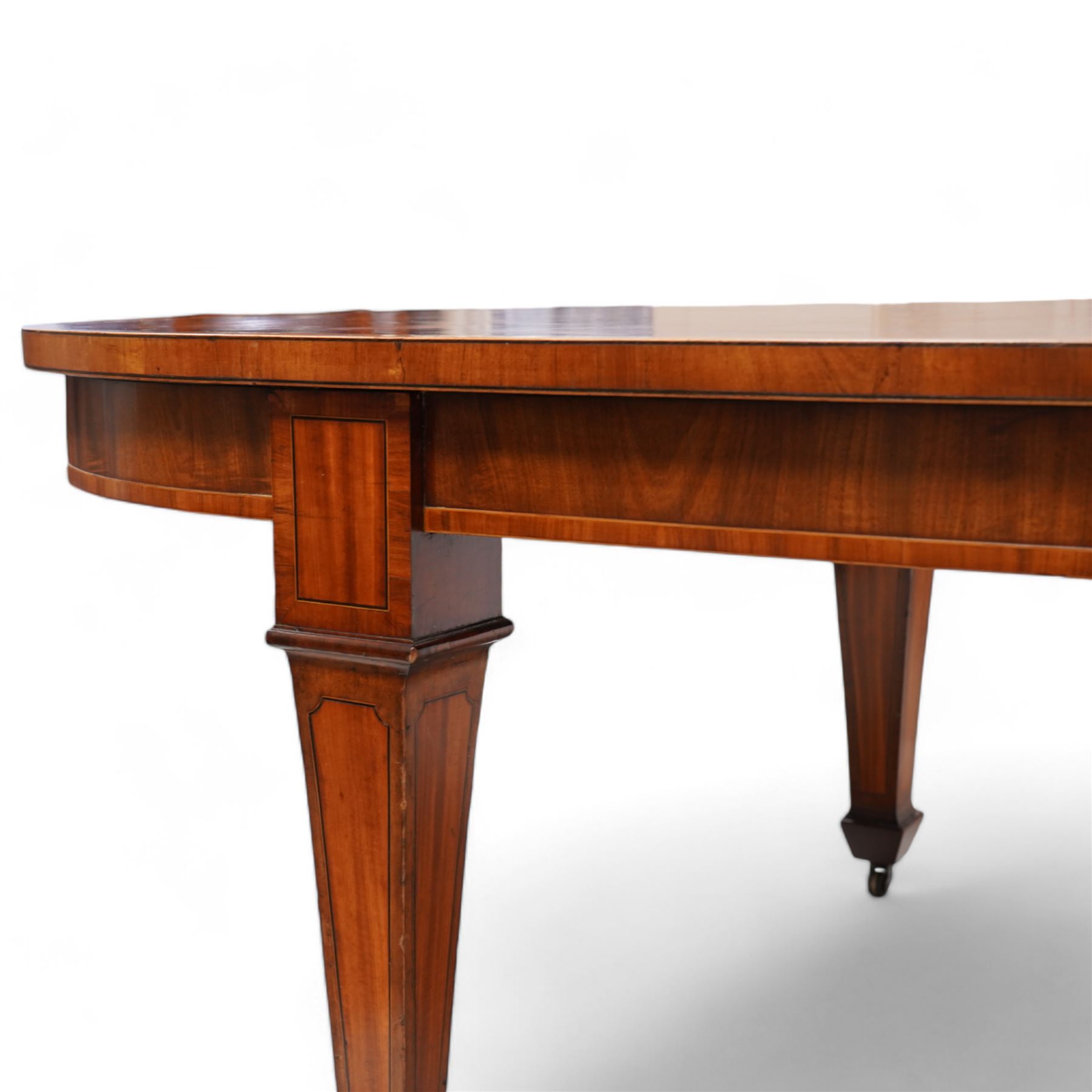 Late 19th to early 20th century mahogany and satinwood banded dining table, telescopic extending action, with three additional leaves, figured frieze rails over square tapering supports with spade feet, inlaid with satinwood panels, on brass castors 