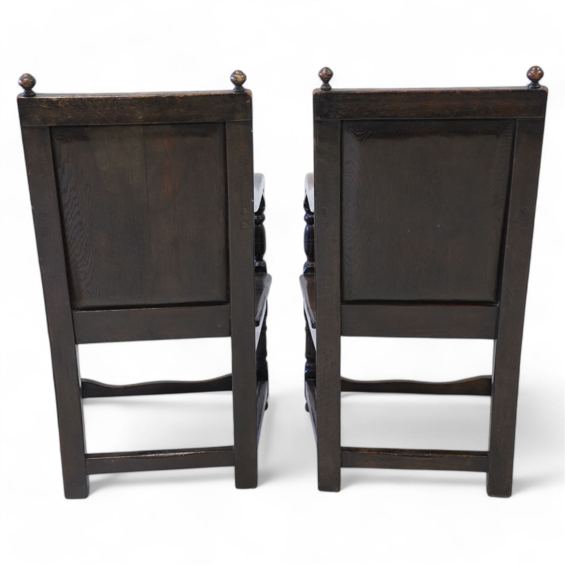 Pair 17th century design wainscot open armchairs, the cresting rail with turned finals over panelled back, the panel carved with geometric pattern and flower heads, shaped arms over plank seat, on turned supports united by stretchers 