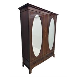 Maples & Co. - Edwardian mahogany wardrobe, projecting cornice over frieze inlaid with checkered stringing, central vertical panel inlaid with lyre and scrolling foliate decoration, two oval mirror glazed doors enclosing hanging rails and hooks, the base fitted with two short drawers, on splayed bracket feet