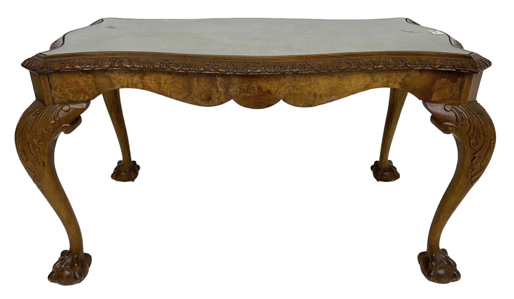 Mid-20th century figured walnut serpentine coffee table, inset glass top and foliate carved edge, raised on cabriole supports with acanthus moulded knees and ball and claw feet