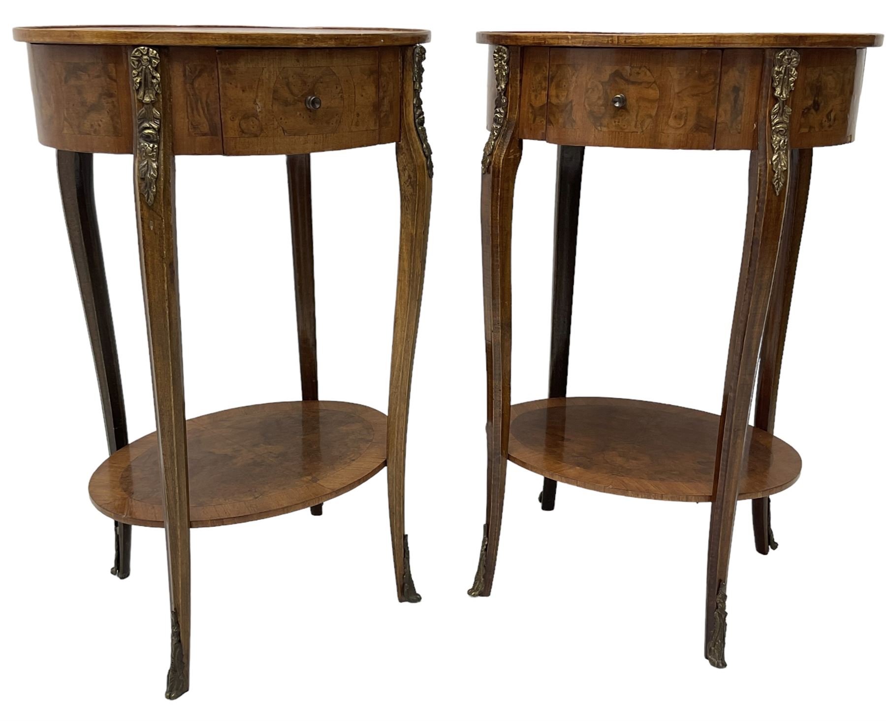 Pair of early 20th century French walnut bedside stands, oval bookmatched and cross-banded top fitted with single drawer, raised on cabriole supports united by undertier, decorated with floral gilt metal mounts