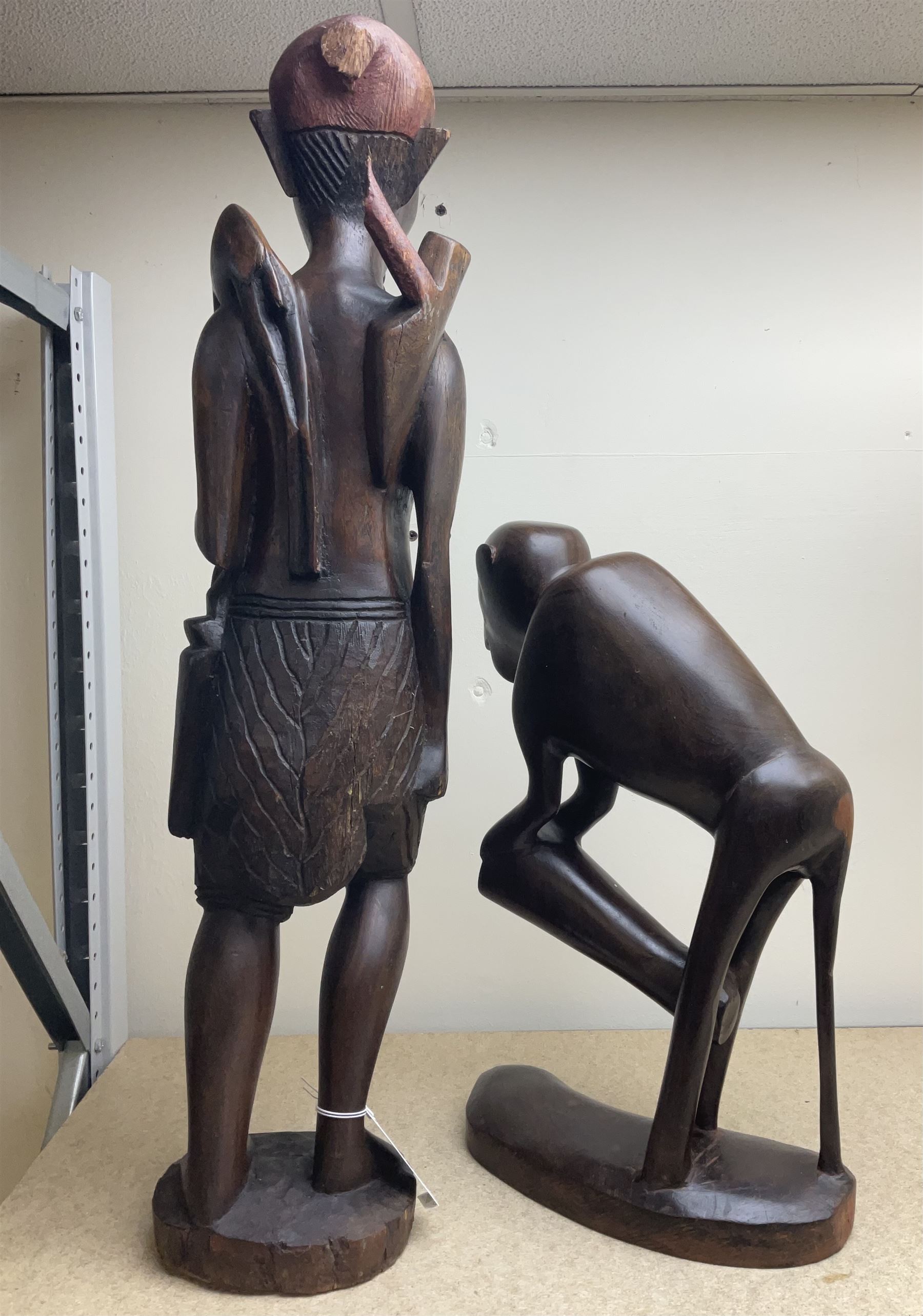 Two African carved hardwood figures, the first carved as a monkey, H43cm, the second as a male figure, H70cm