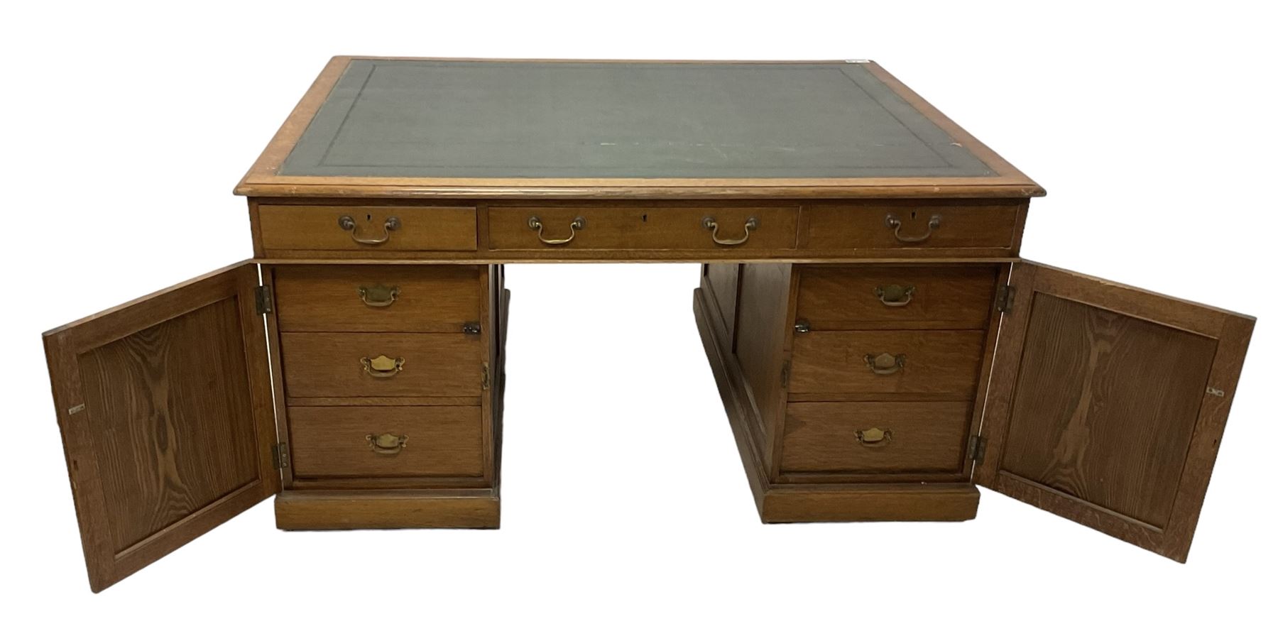 Late 19th century twin pedestal oak partner's desk, rectangular top with inset green leather writing surface, fitted with nine graduating drawers to each side, the rear drawers enclosed by panelled cupboards