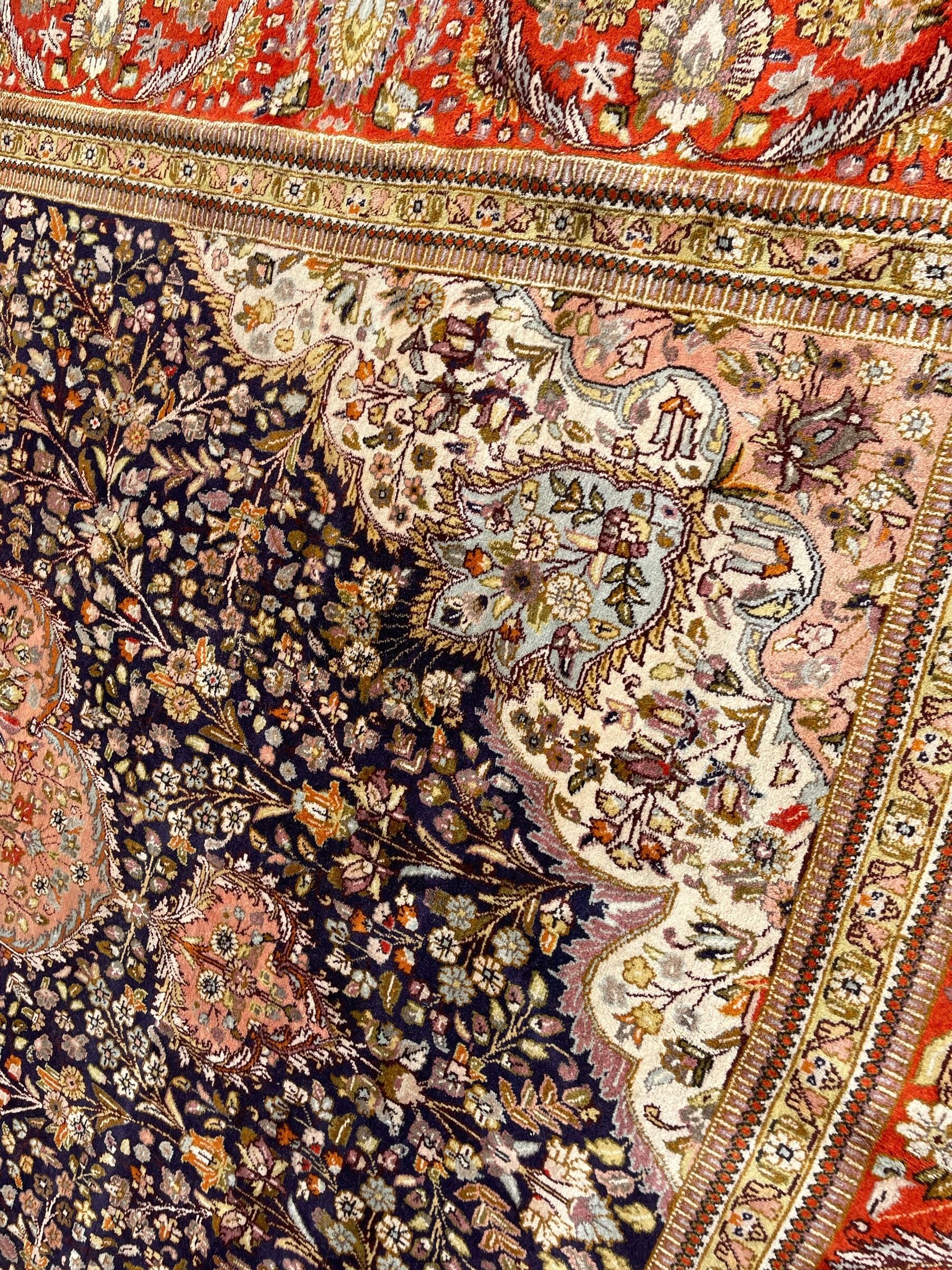 Persian Kashan, scalloped central medallion on indigo ground field, decorated profusely with branch shoots with floral motifs, pale ground spandrels decorated with stylised flower head motifs, crimson ground border decorated with repeating palmettes and trailing leafy branches, within multiple guard stripes 