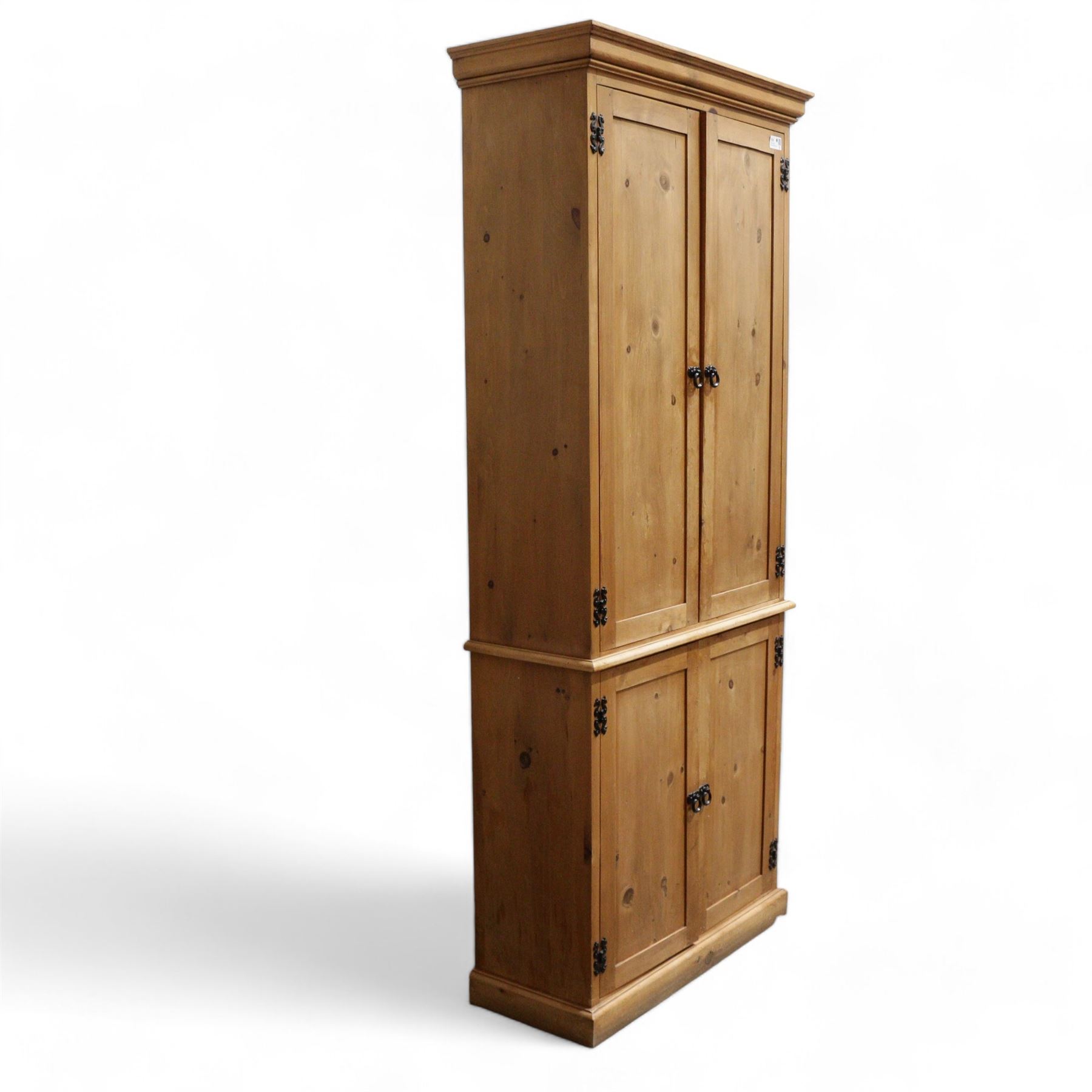 Tall 20th century stained pine cupboard, projecting cornice over four panelled cupboard doors, enclosing shelves, on skirted base, with iron fittings and handles