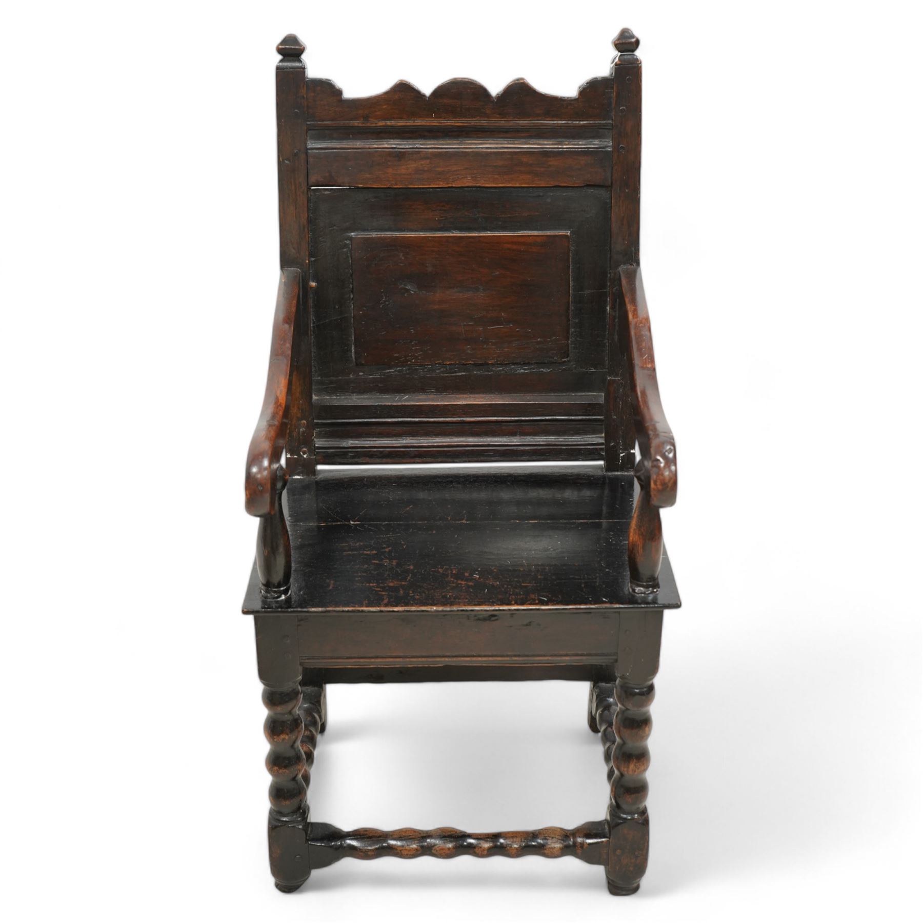 17th century and later oak wainscot chair, shaped cresting rail over panelled back, down sweeping dished arms over plank seat, on bobbin turned supports united by bobbin turned stretchers 