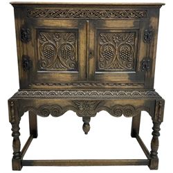 Jacobean Revival carved oak cupboard, moulded rectangular top over S-scroll carved frieze and two doors, the panelled doors carved with stylised plant motifs, on stand decorated with lunettes and shaped apron with hanging turned pendant, on turned supports united by stretchers 