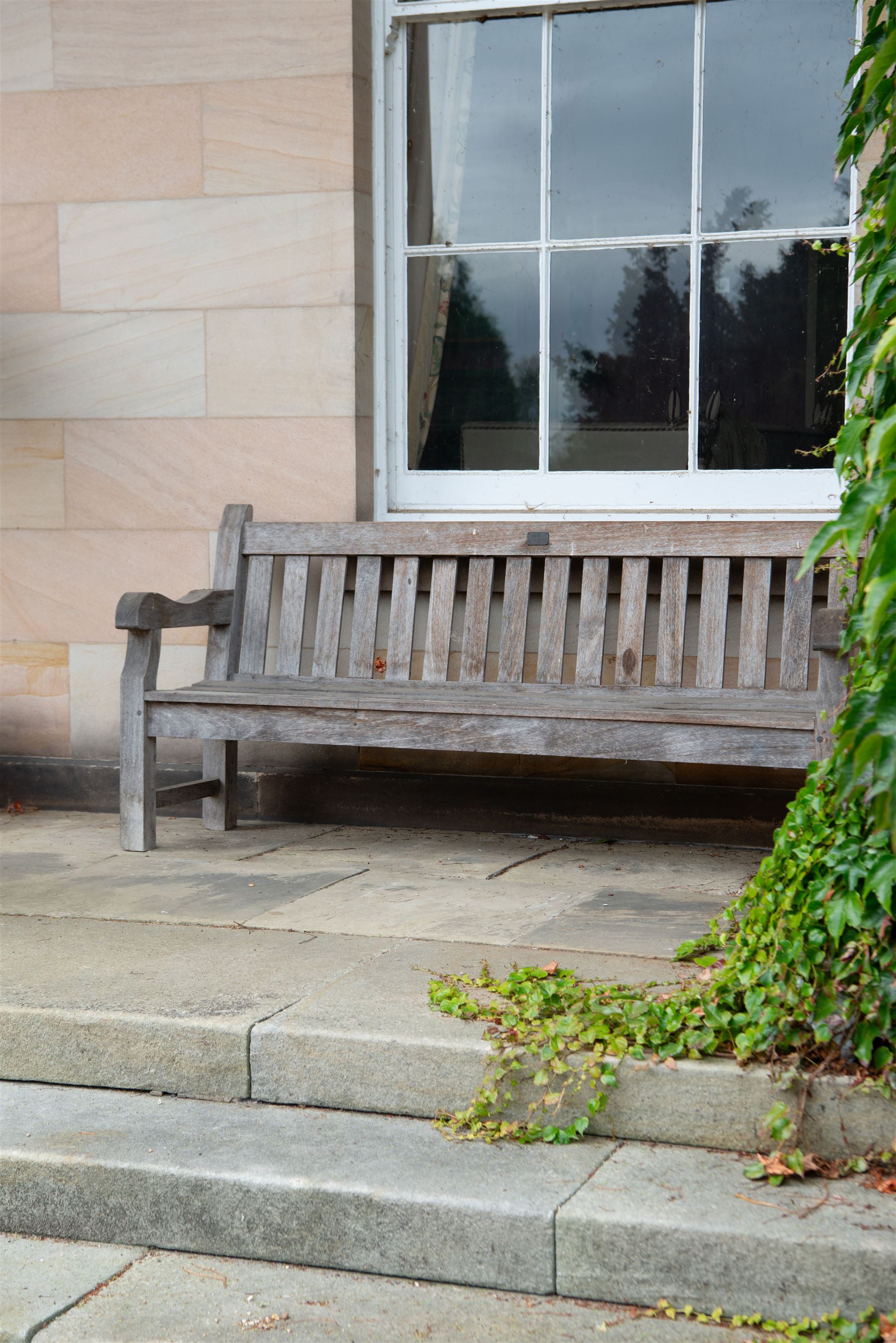 'J.V.T. Ampleforth' - teak garden bench, plain cresting rail with applied maker's plaque over slatted back and seat, on square supports 