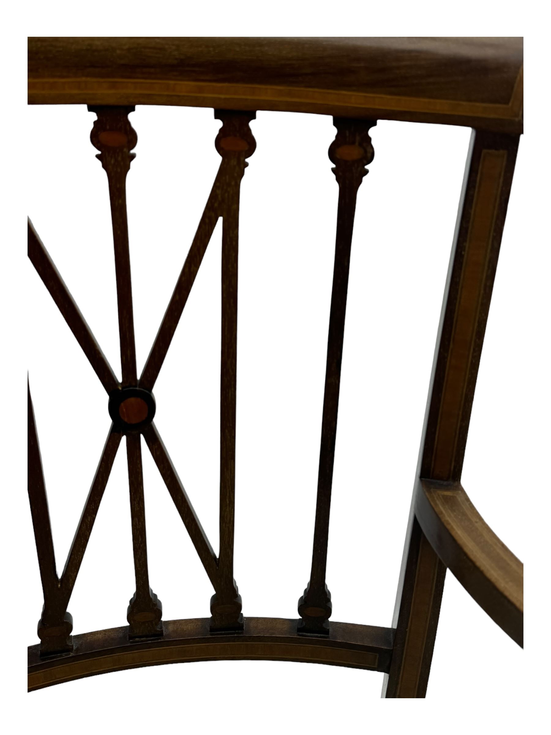 Edwardian inlaid mahogany armchair, curved top rail above spindle backrest with central X-shaped splat, the arms supported by turned uprights, over upholstered padded seat in pale blue damask fabric, on tapered supports with spade feet