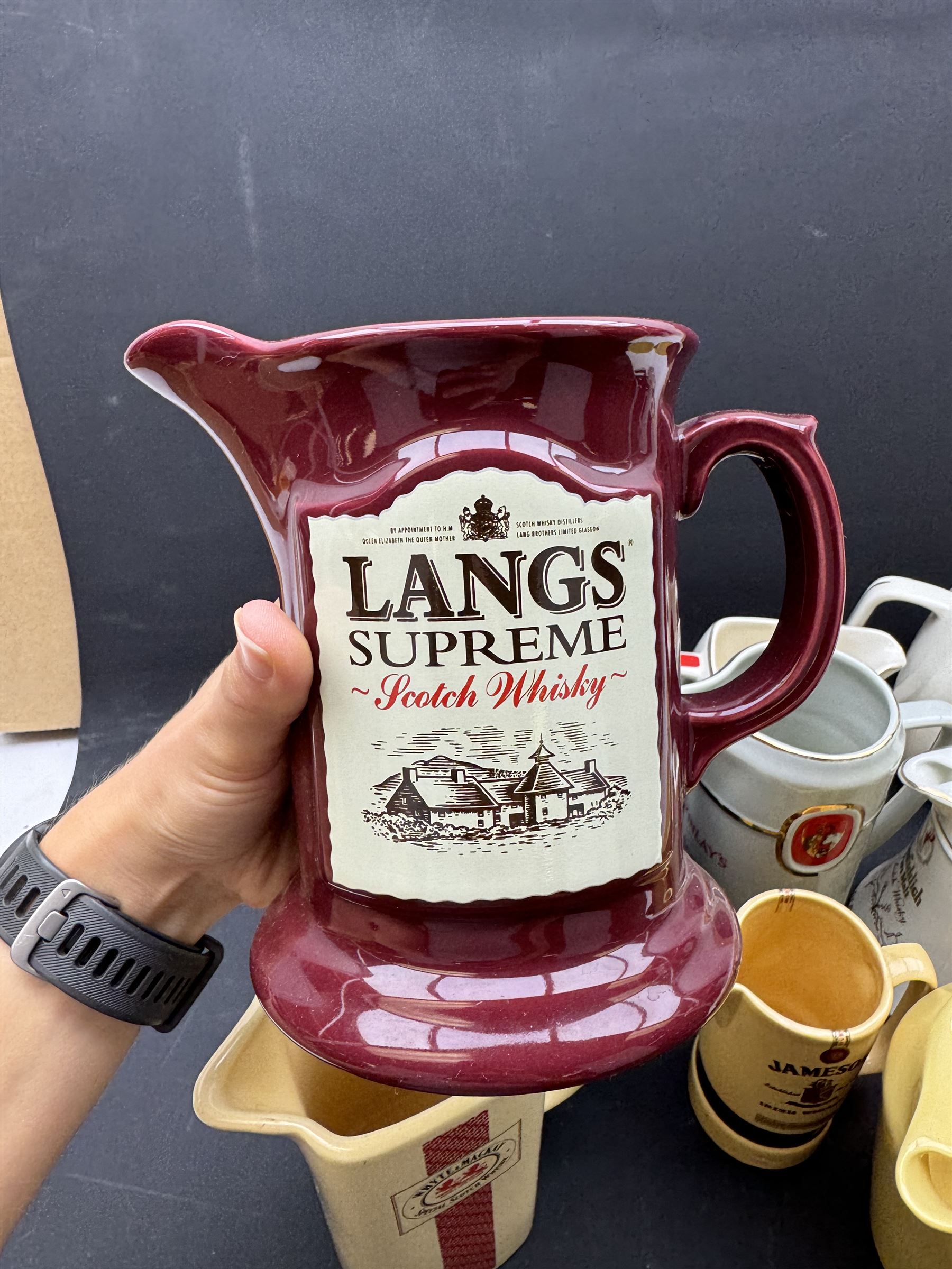 Eighteen ceramic whisky jugs bearing various advertising, including Cutty Sark, White Horse, Bells, Langs Supreme etc 