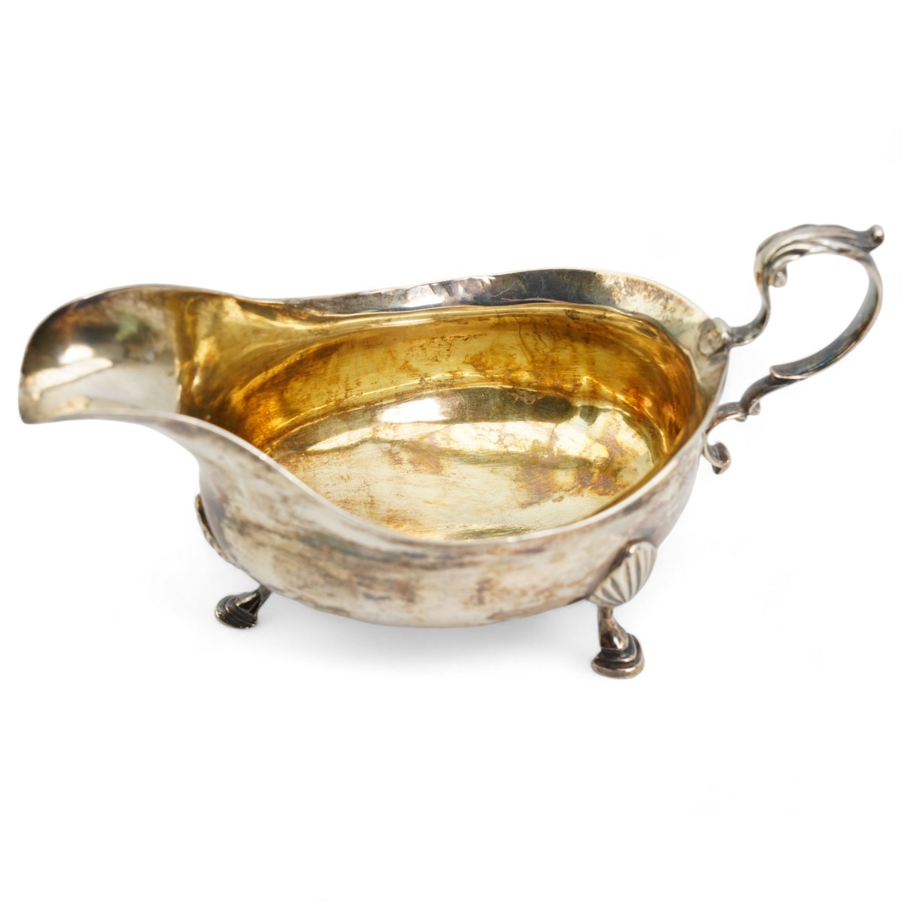 George III silver sauce boat with leaf capped scroll handle and shaped supports, Newcastle assay Maker John Langlands I and John Robertson I and a silver cream jug Birmingham 1907 