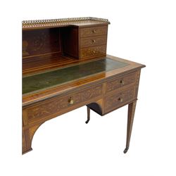 Edwardian inlaid mahogany writing desk, raised galleried back over inlaid central urn with scrolling leafy branches and six small drawers, satinwood banded rectangular moulded top with tooled leather inset, fitted with five drawers, the drawer facias inlaid with scrolling foliage and satinwood banding, square tapering supports inlaid with trailing bell flowers, on brass and ceramic castors 