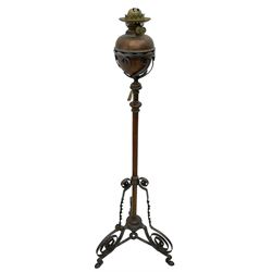 Late 19th to early 20th century wrought metal and copper telescopic oil standard lamp, the lamp and reservoir on scrolled supports with waved band, handle operating telescopic action, tripod base with scrolled terminals and twisted decoration, splayed pad feet 