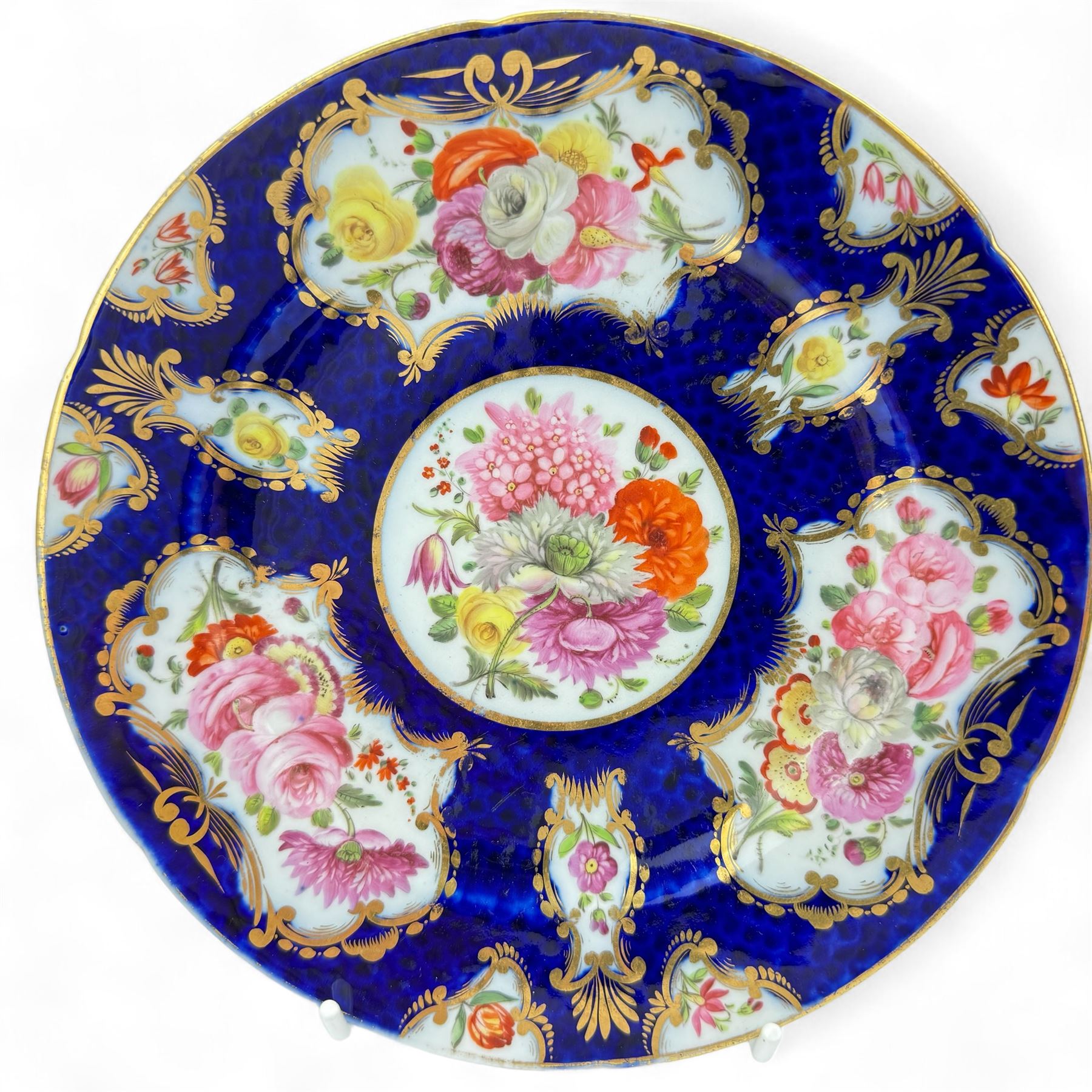 Pair of early 19th century plates, each painted with summer flowers within gilt fan shaped reserves, against a blue scale ground, unmarked, D19cm, together with a 19th century English porcelain plate, pattern no. 2/1078 (3)