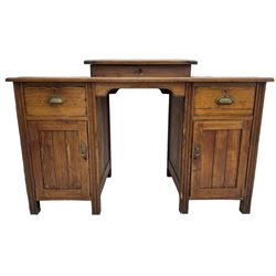 Edwardian pitch pine desk, rectangular top with writing slope flanked by inset leather writing surfaces, over twin pedestals each with shell cup handled drawer over cupboard, the left enclosing two shelves, the right enclosing sliding trays, on fluted straight supports