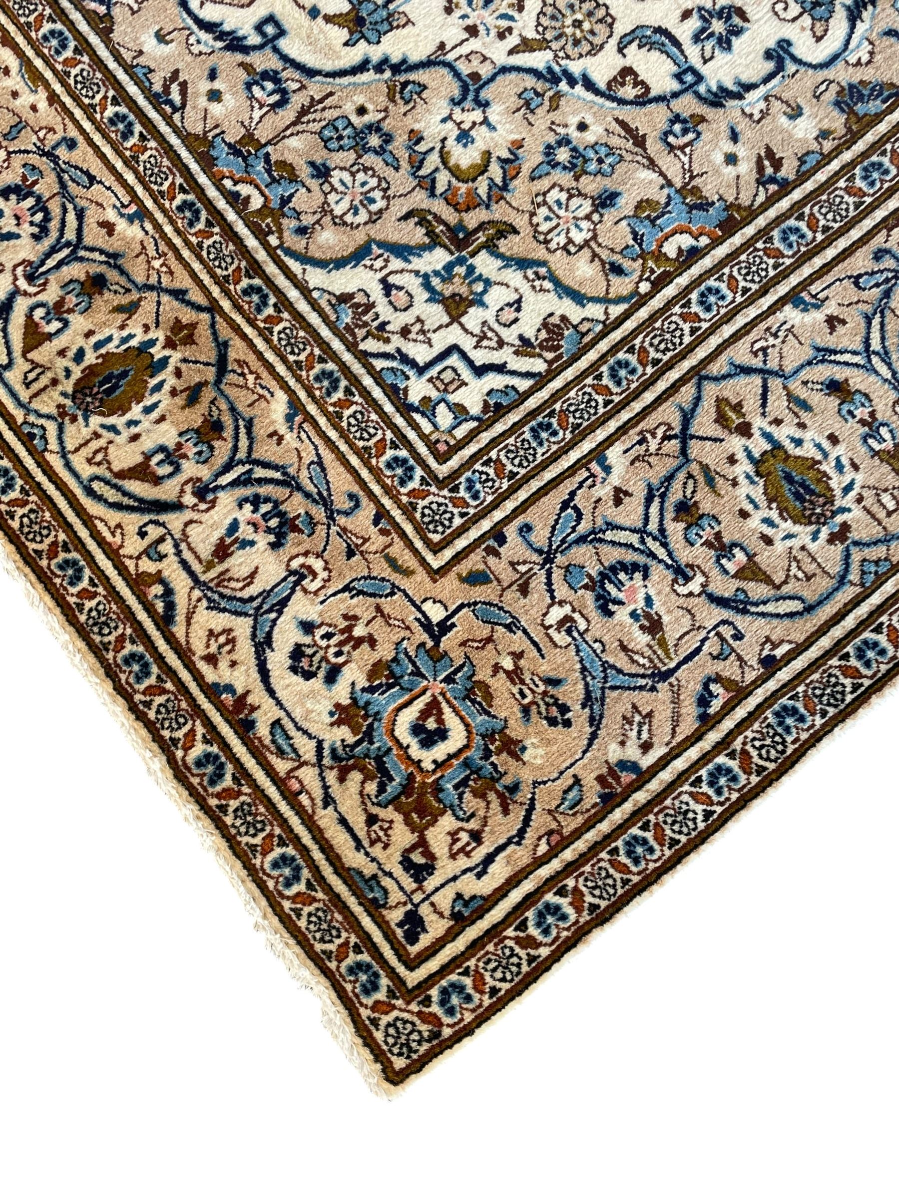 Persian Kashan ivory ground rug, the field decorated with interlacing branches and palmettes, central floral design pole medallion, the scrolling border decorated with stylised plant motifs, within repeating flower head guard stripes