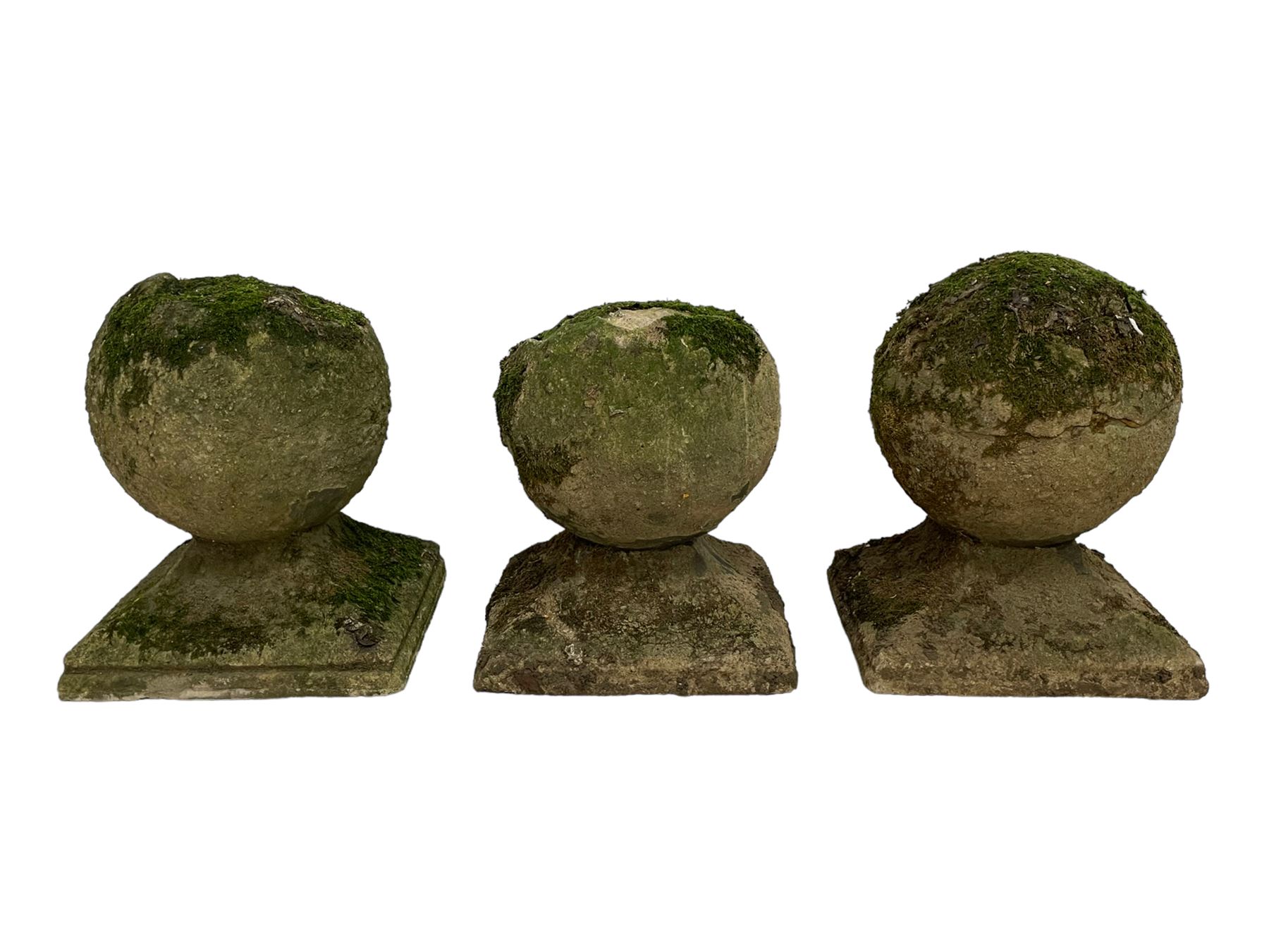 Set of three weathered cast stone gate post finials, circular orb on step-canted square base 