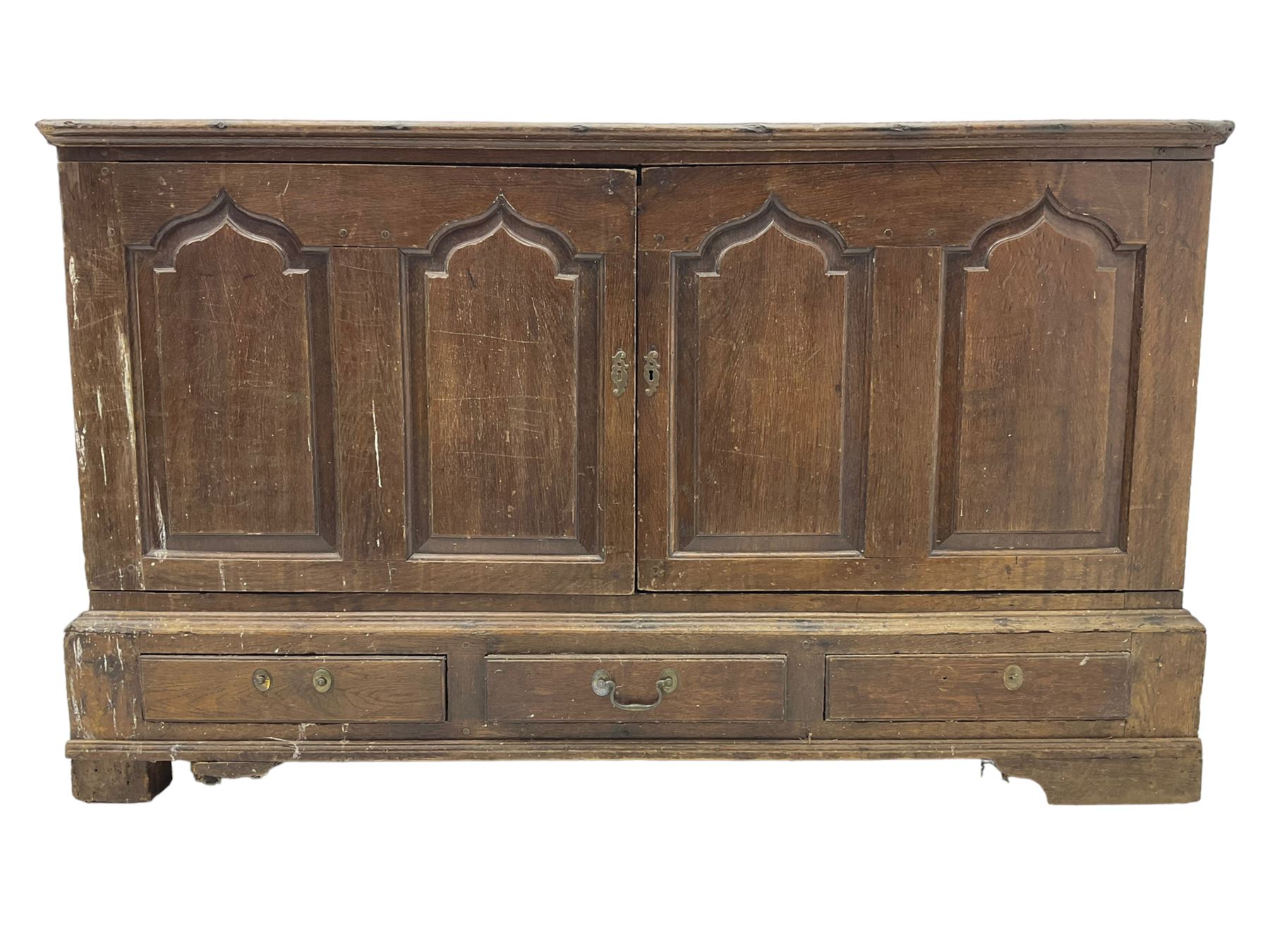 Georgian oak converted mule chest, rectangular plank top over two cupboards with arched Gothic motif panels enclosing storage area with shelves, the base with three drawers with pull handles, on shaped bracket feet