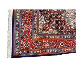 Persian Bidjar ivory and indigo ground rug, large central rosette medallion surrounded by floral herati motifs, crimson ground border decorated with repeating palmettes, within guard stripes decorated with small flower head motifs 