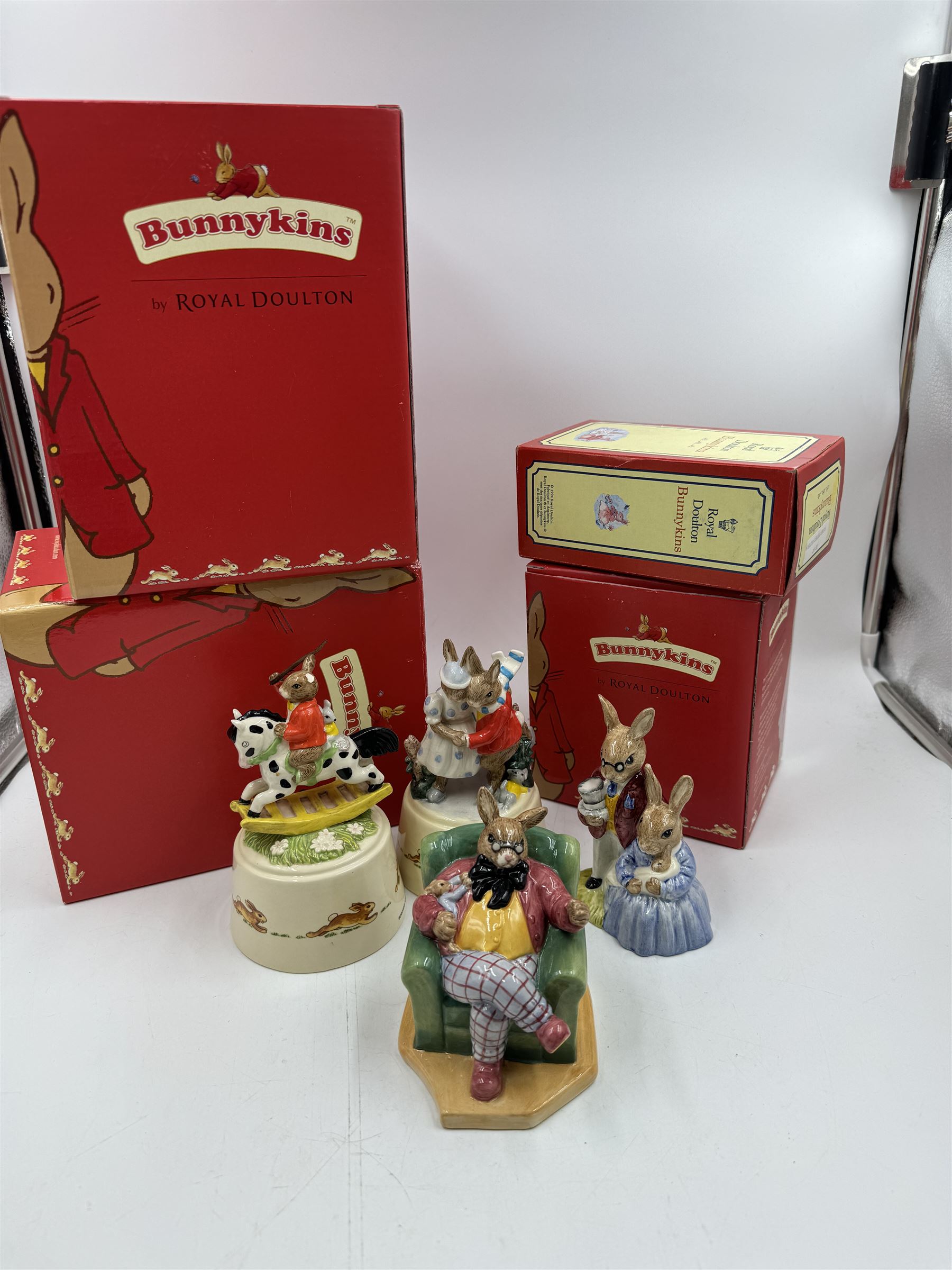 Two Royal Doulton Bunnykins music boxes, comprising Rocking Horse and Winter Waltz together with two Royal Doulton Bunnykins figures Once Upon a Time and Father, Mother & Victoria, all with original boxes  