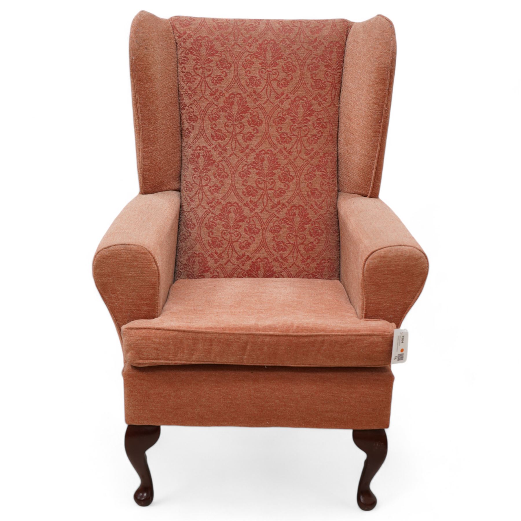 Hardwood-framed wingback armchair, upholstered in peach fabric, on cabriole feet 