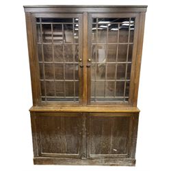 20th century beech bookcase on cupboard, the top section enclosed by two glazed doors, the lower section enclosed by two panelled doors, on plinth base