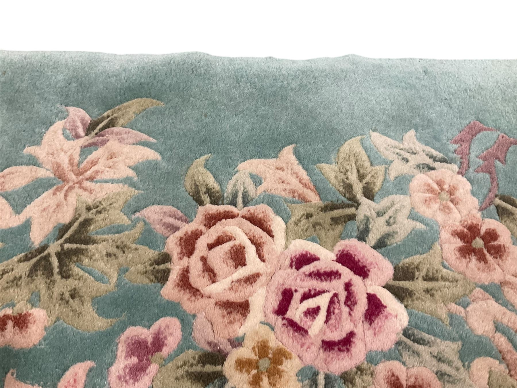 Chinese pale turquoise ground washed woolen rug, the plain field decorated with two large floral bouquet motifs with extending blossom and leafage