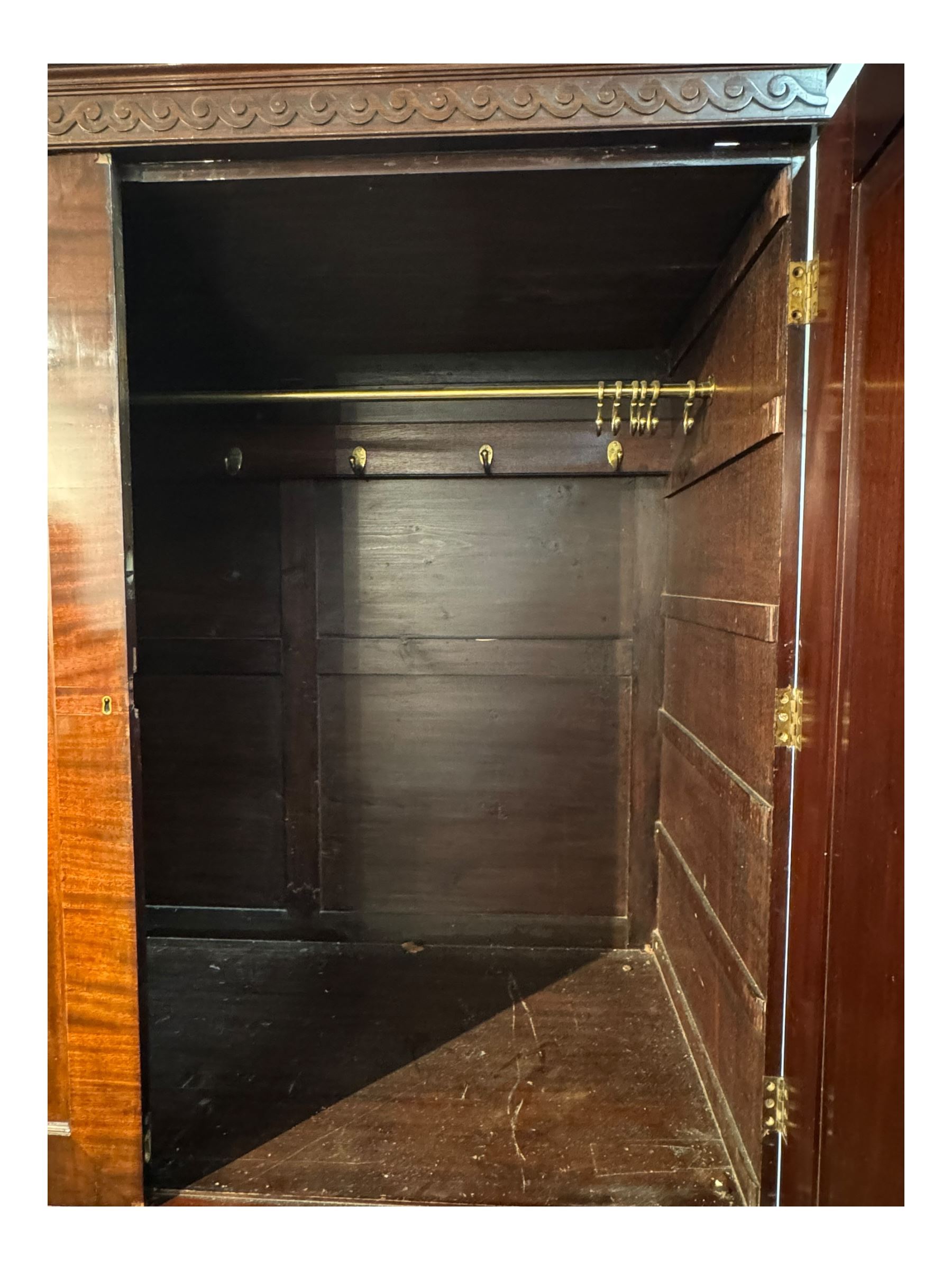 Victorian mahogany linen press, projecting cornice with dentil and scroll detailing, double panelled doors opening to an interior fitted with a brass hanging rail and coat hooks, lower section with two drawers and fitted shelves for additional storage, raised on bracket feet