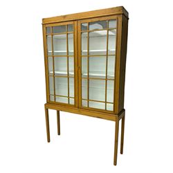 Georgian stripped pine bookcase display cabinet, plain moulded cornice over two glass-panel doors with multiple panes, enclosing white painted interior with three shelves, raised on square supports