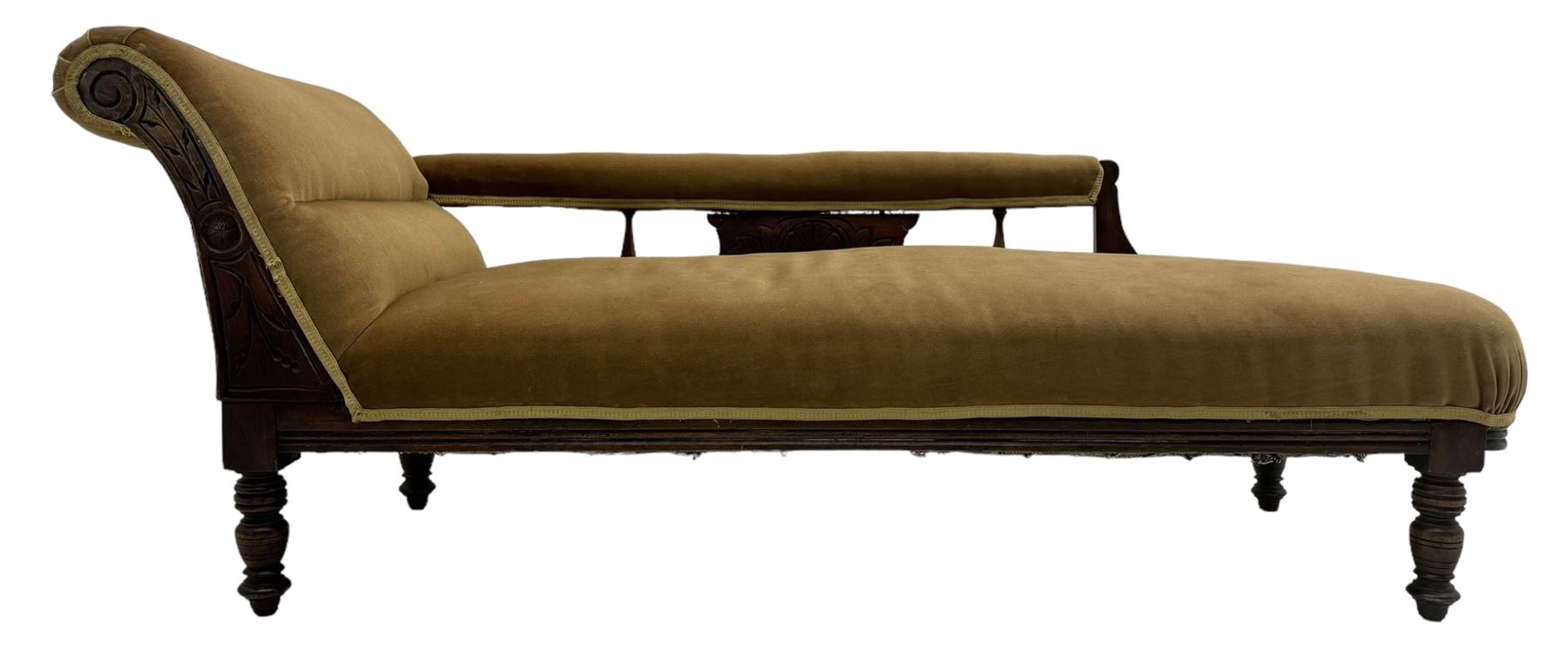 Late 19th century mahogany framed chaise longue, upholstered in tan fabric, featuring scrolled backrest with carved floral motifs, supported by turned legs