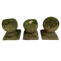 Set of three weathered cast stone gate post finials, circular orb on step-canted square base 