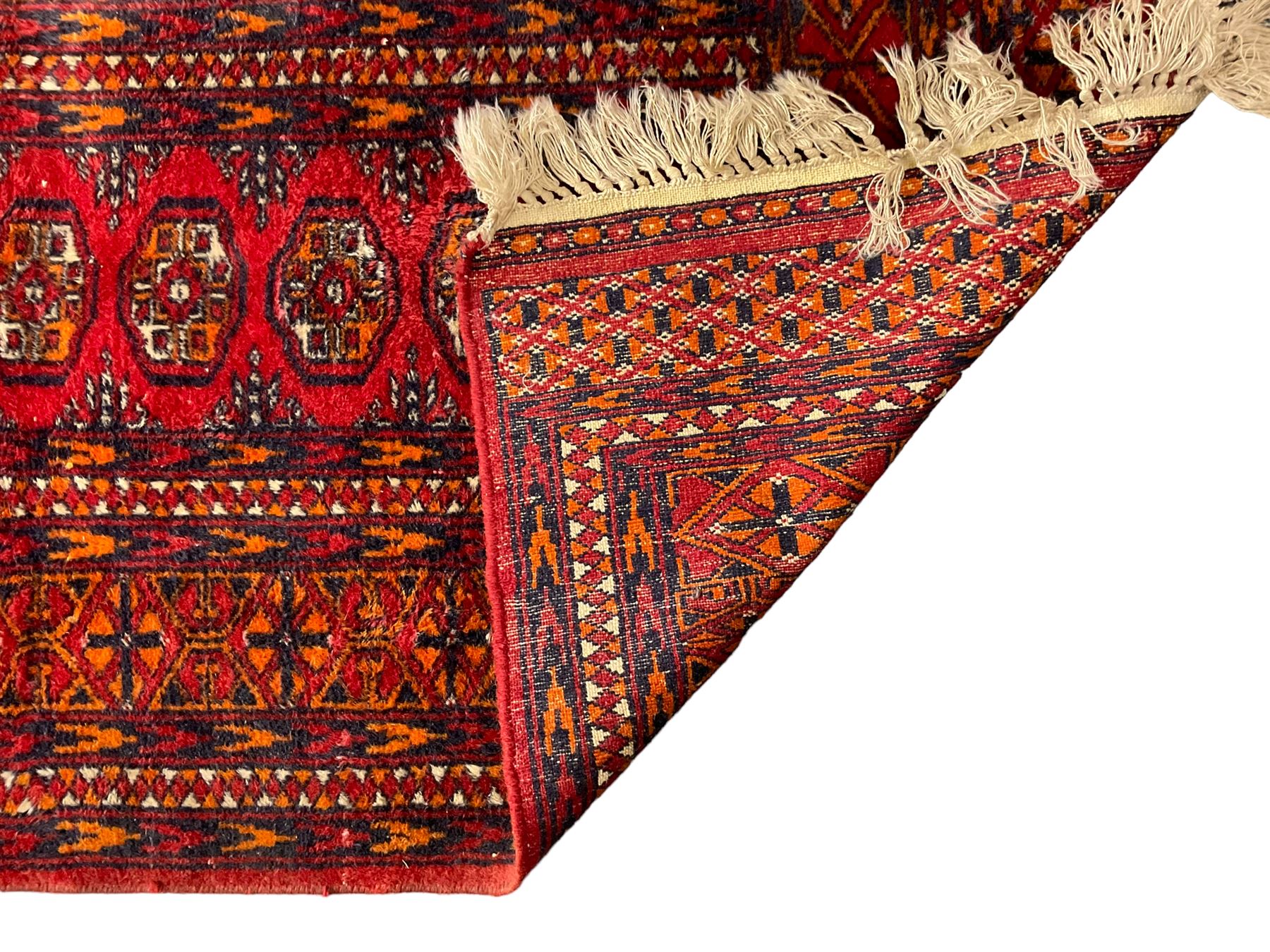 Persian Bokhara dark amber round rug, crimson field with six Gul motifs, surrounded by a guarded border with geometric design (124cm x 70cm); together with another similar in amber and red (101cm x 63cm) (2)