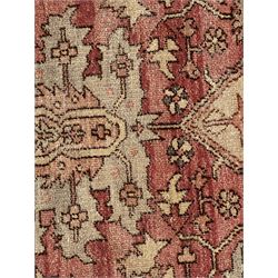 Persian Heriz design rug with red ground, the field featuring a central medallion with floral and geometric motifs, surrounded by ivory spandrels, the main border showcasing a series of floral patterns on a dark blue ground