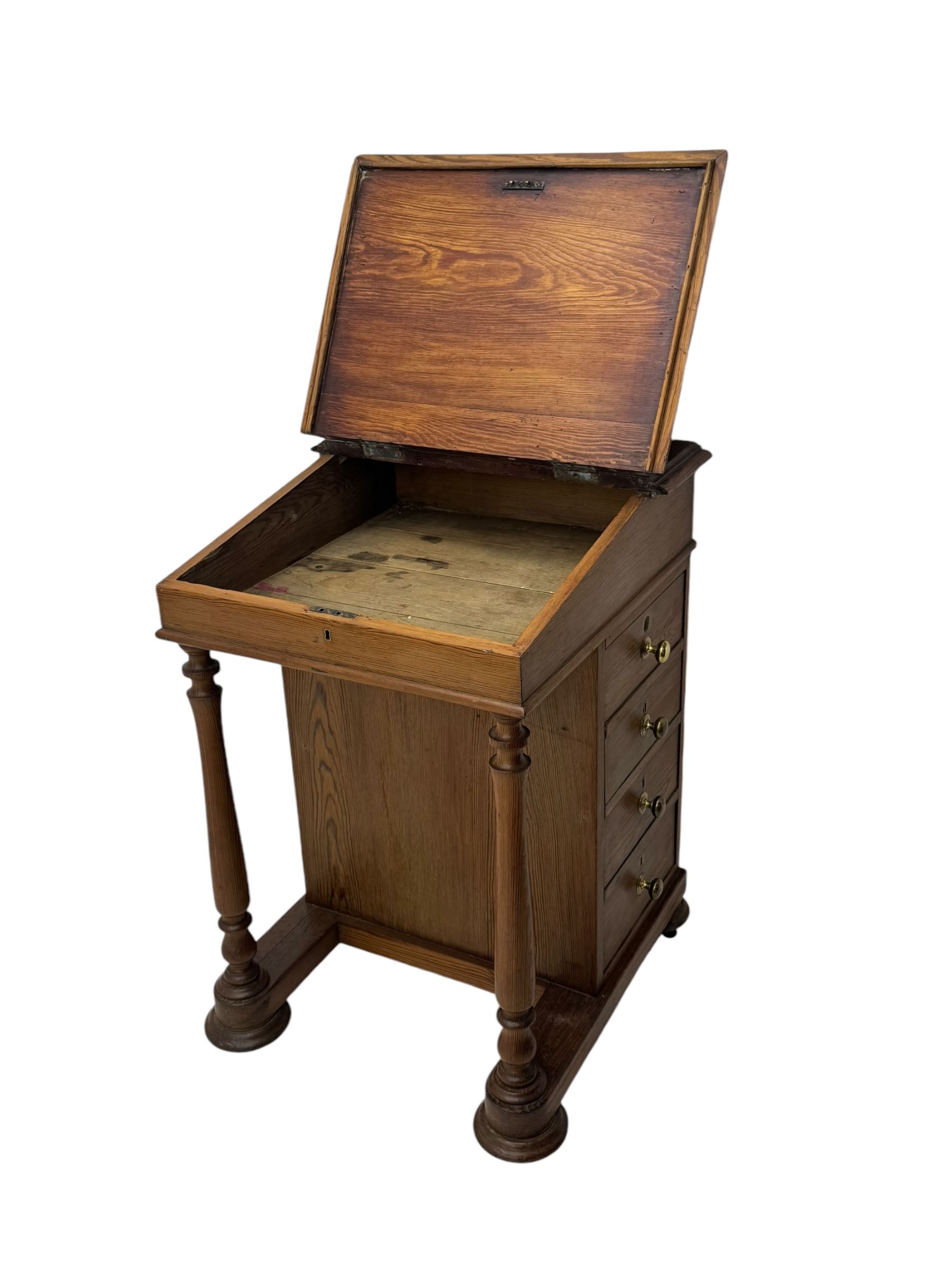 19th century pitch pine Davenport desk, sloping hinged top, fitted with four drawers, on turned column supports, turned compressed feet with castors 