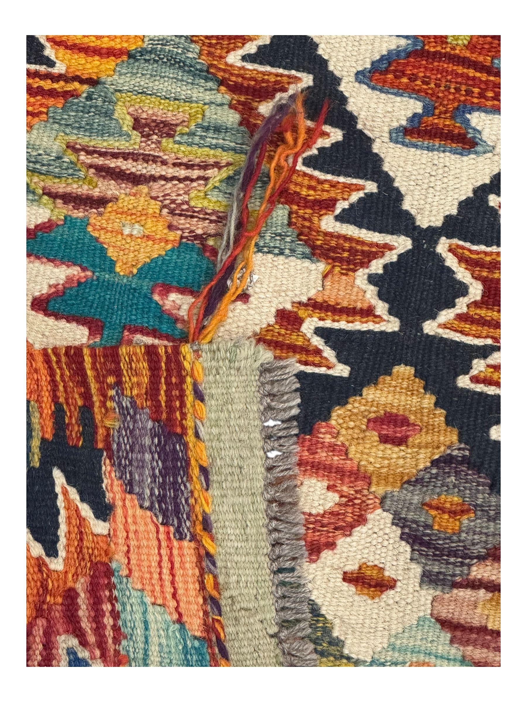 Chobi Kilim multicoloured ground runner, displaying diamond-shaped motifs in shades of blue, red, yellow, and green, accented by a bold black outline and bordered with a striped design, flatwoven with fringed edges