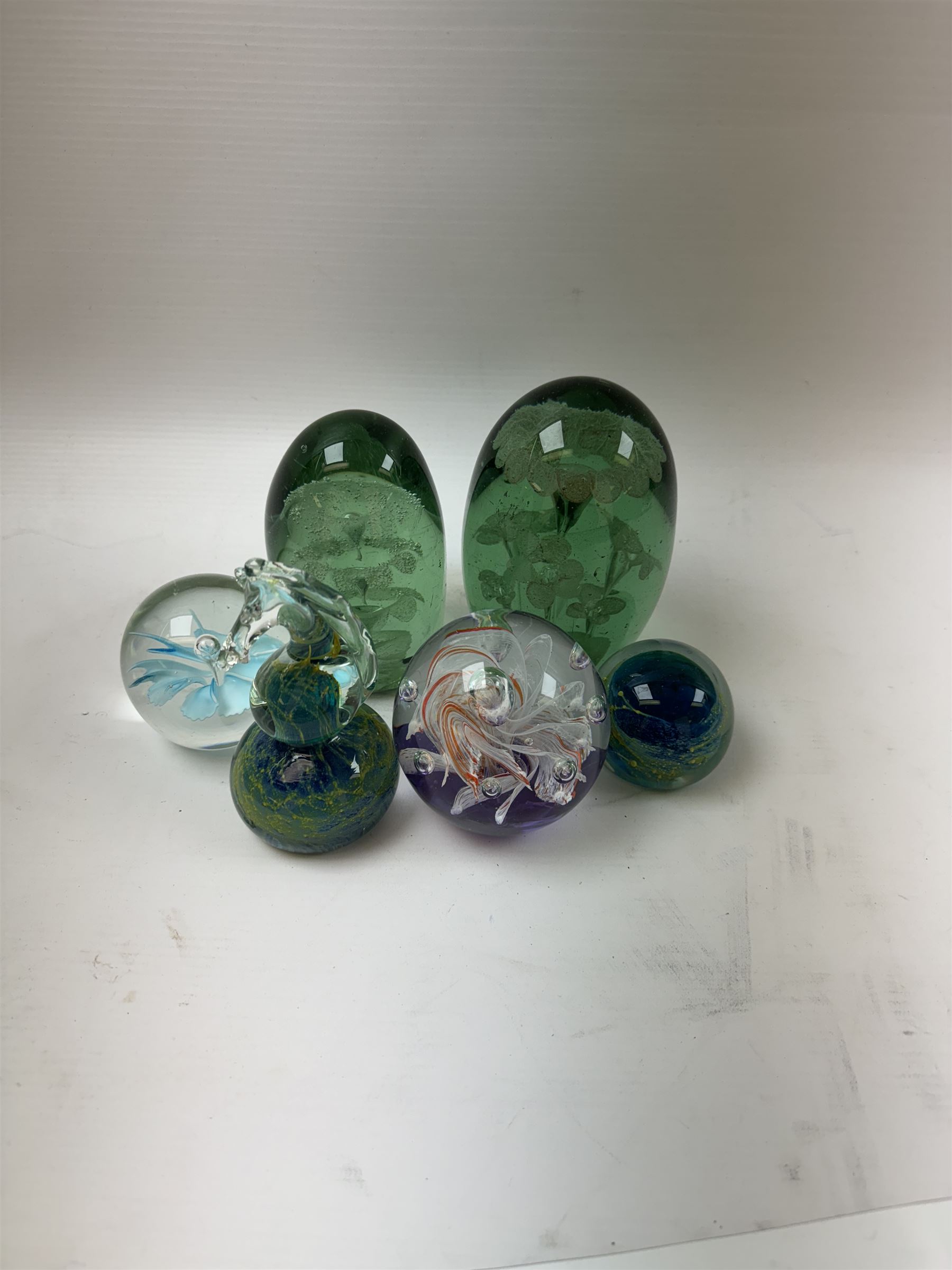 Two glass dump paperweights, with flower inclusions, together with four further glass paperweights